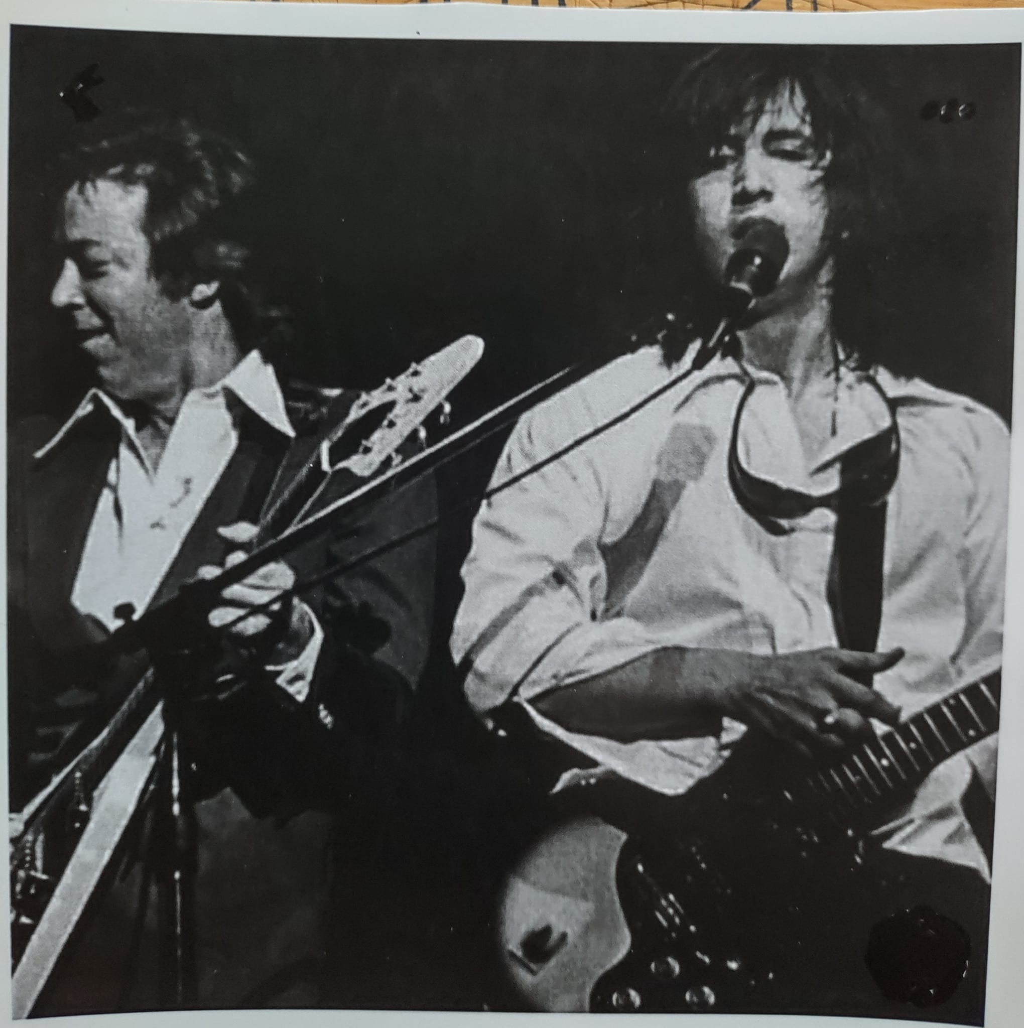 Two guitarists side by side on stage — black-and-white close-up live shot