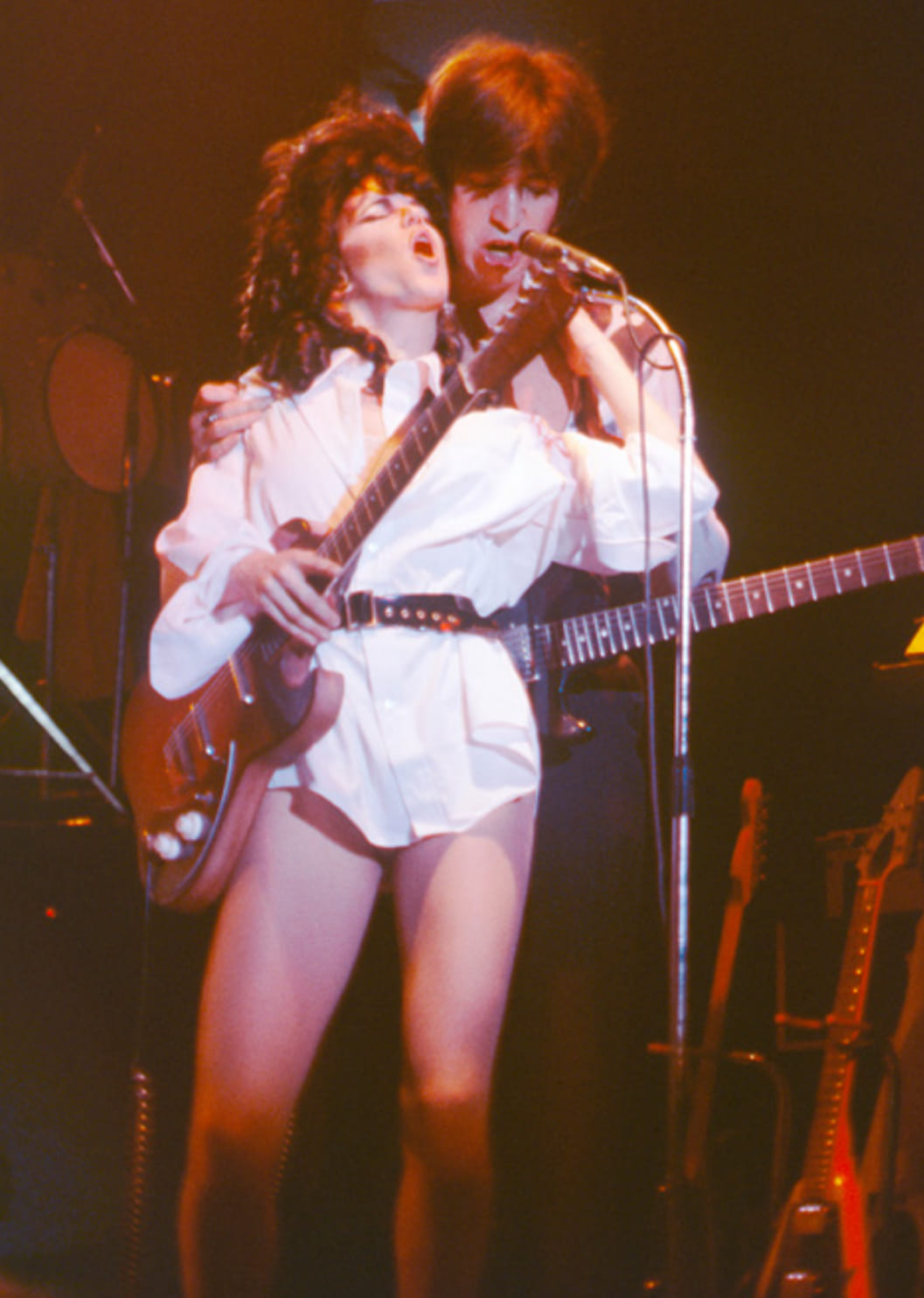 Bill Spooner singing at the mic with a woman in a white shirt on stage — live color shot