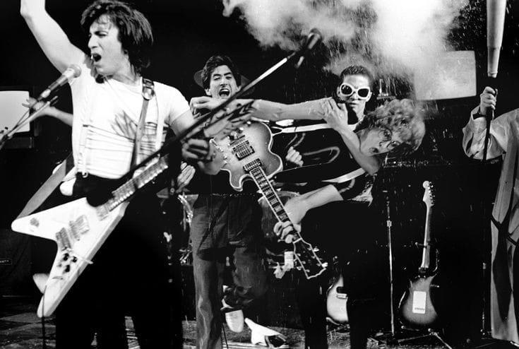 The Tubes in full chaos — Bill Spooner on Flying V far left, band members mid-leap and mid-action, black-and-white