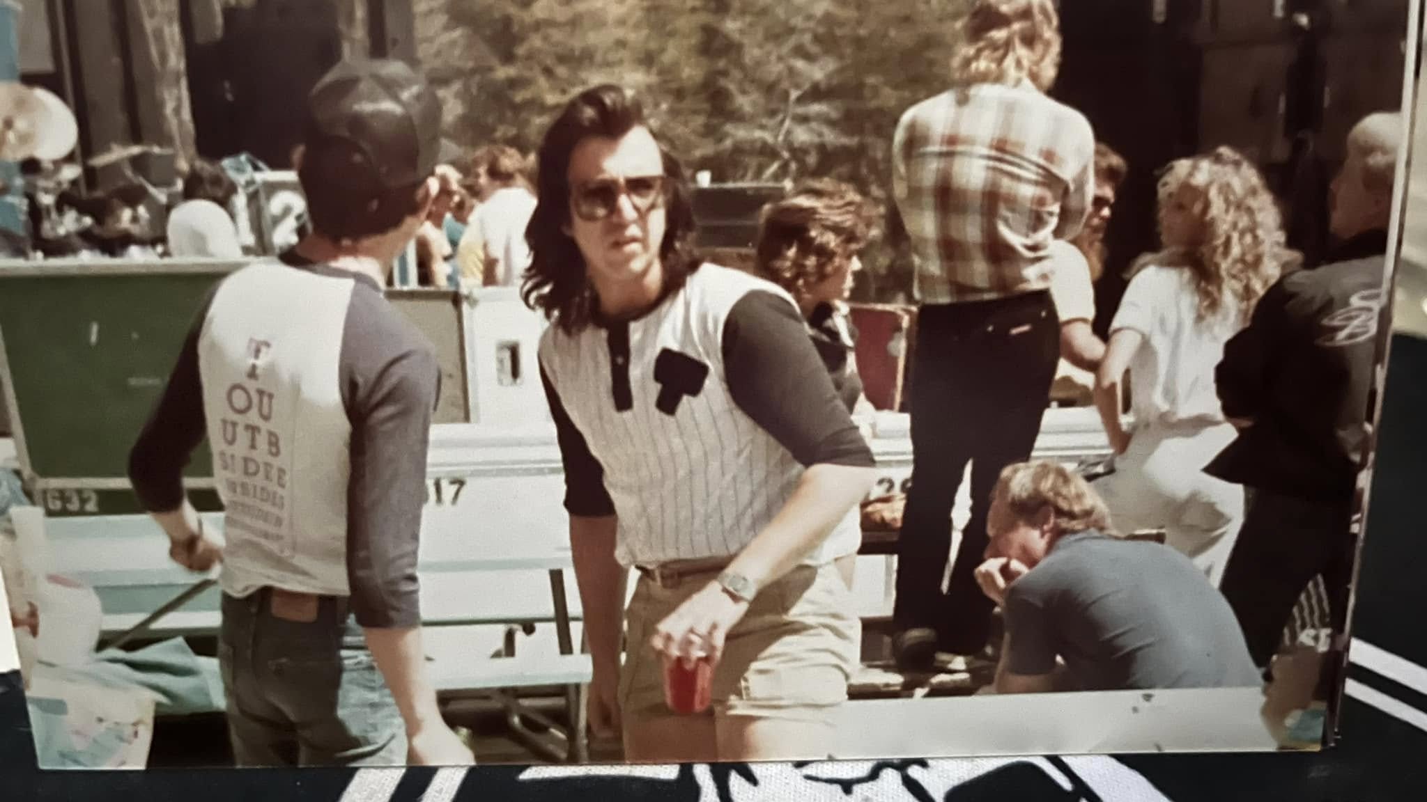 Bill Spooner in a pinstripe baseball shirt and sunglasses at an outdoor festival — candid color backstage shot