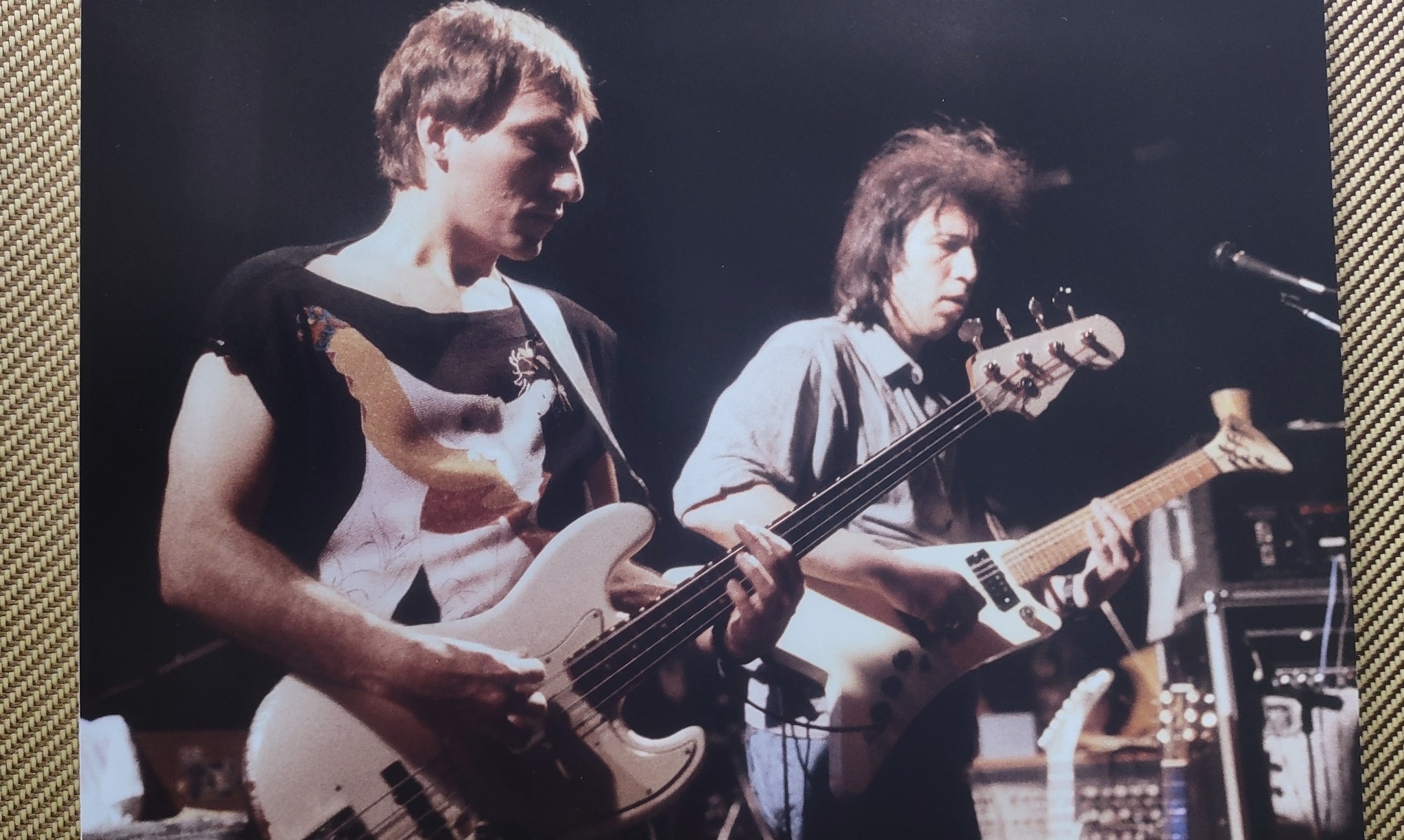 Two musicians on stage in color — guitarist and bassist side by side, mid-performance