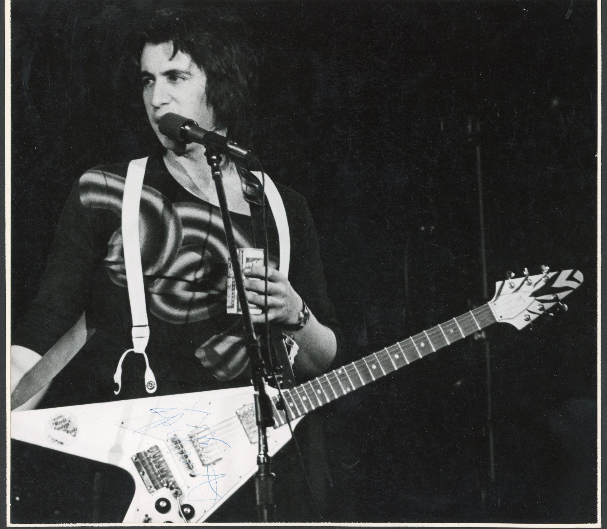 Bill Spooner singing at the mic with his white Flying V, black-and-white live shot