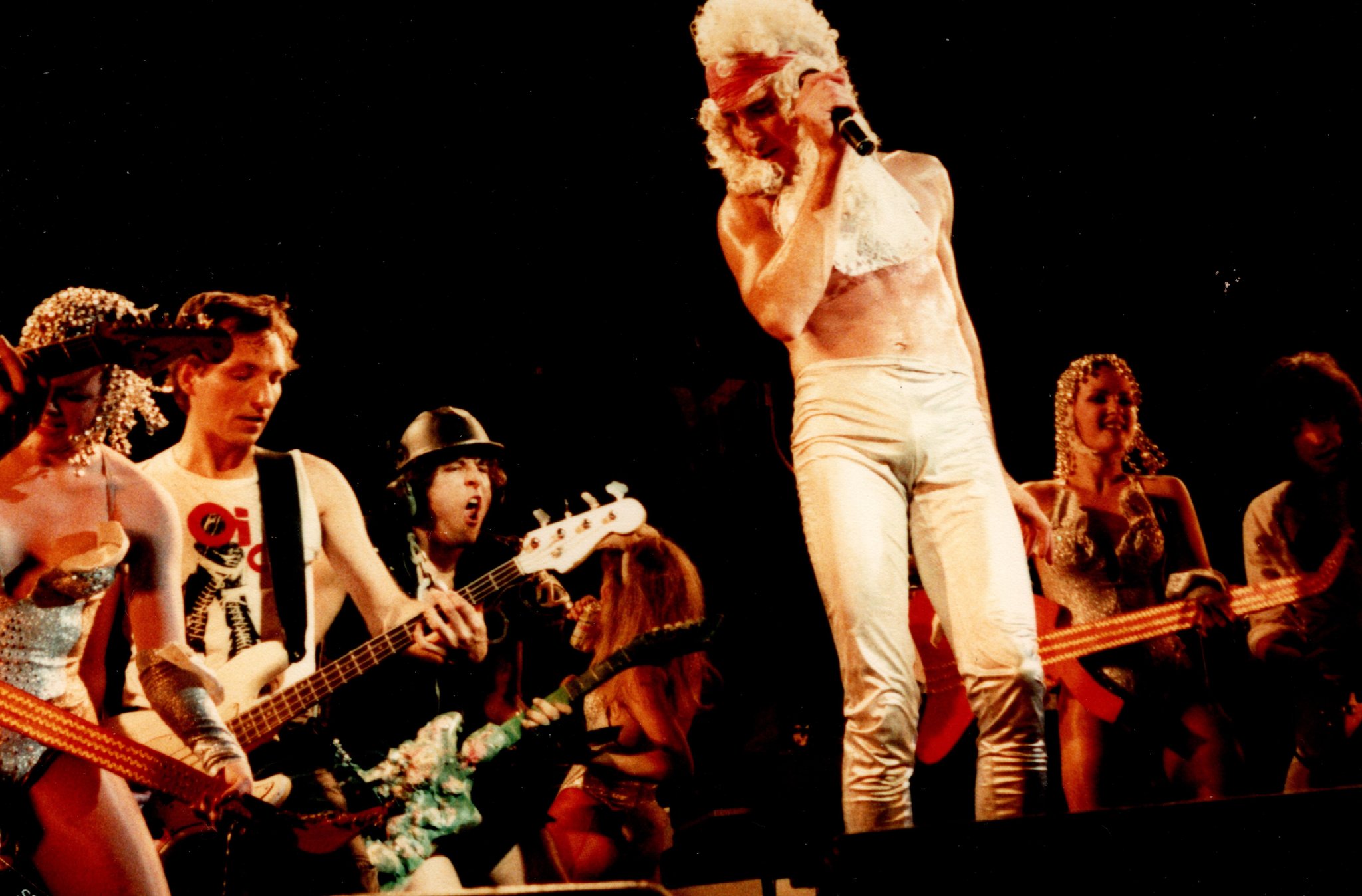 The Tubes theatrical ensemble on stage — Fee Waybill in white wig and costume, band and dancers in golden brocade costumes, color