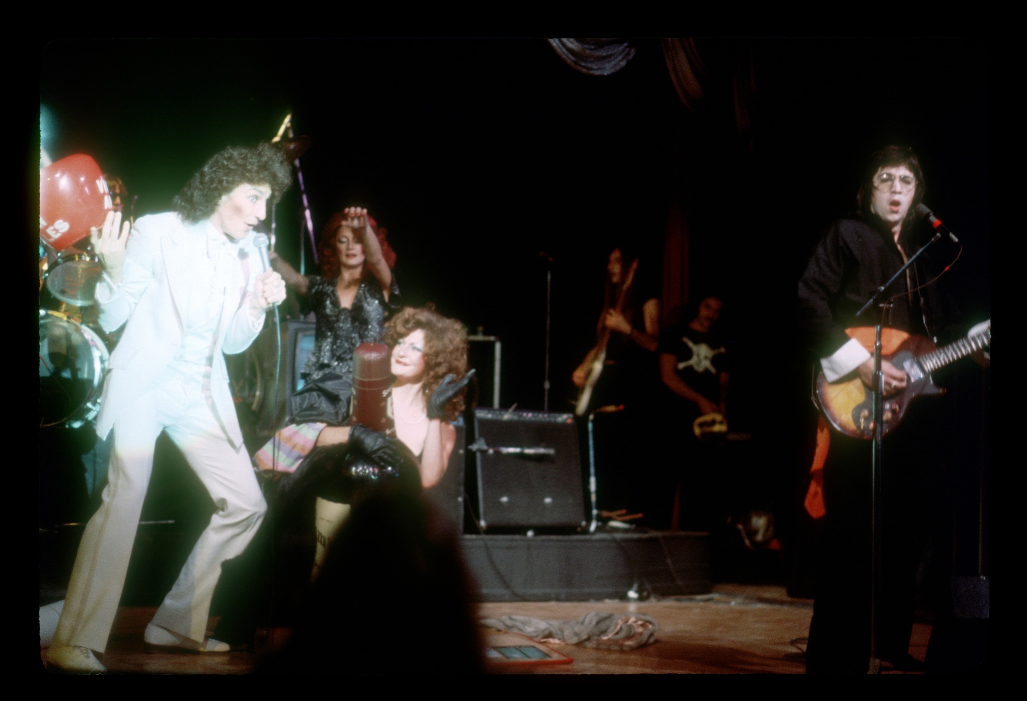 The Tubes on stage in color — Fee in a white suit, Re Styles kneeling center, Roger Steen on guitar at right